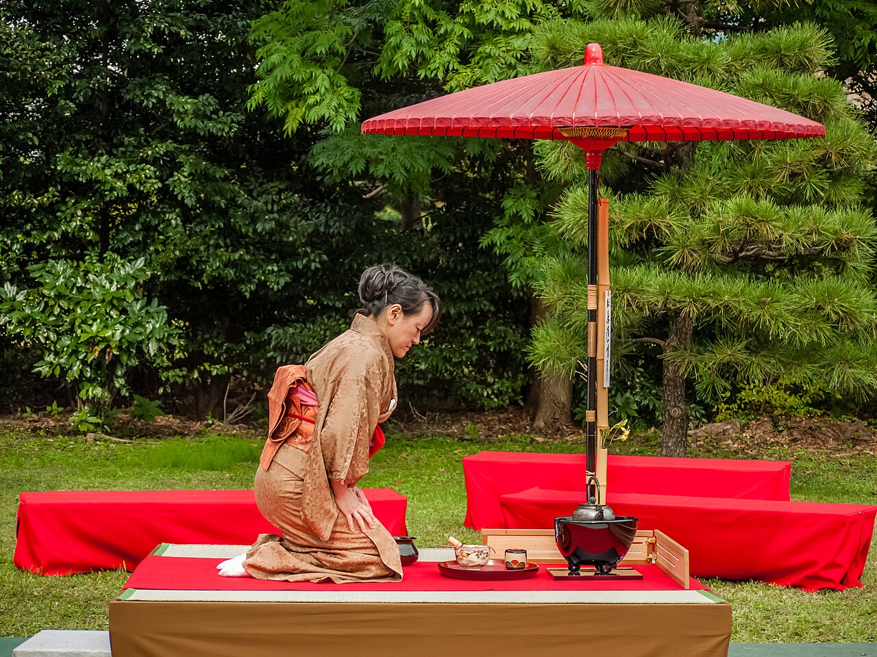 Cérémonie du thé matcha (chanoyu) : hôte en kimono préparant le matcha au chasen sous une ombrelle rouge
